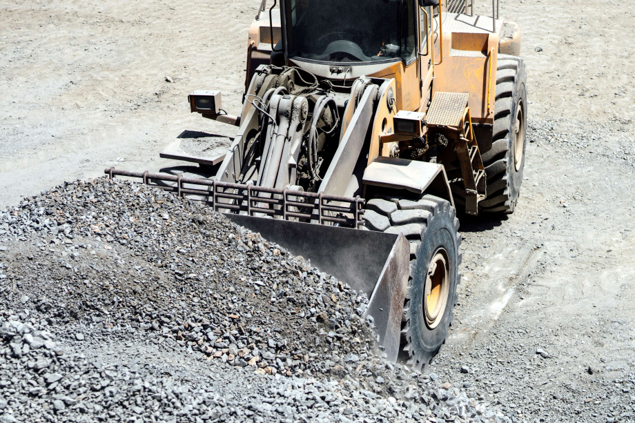 A front-end loader collects crushed rock.