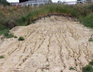Soil on a slope with multiple rills caused by rain going down the slope. The rills look like very small dried up streams.